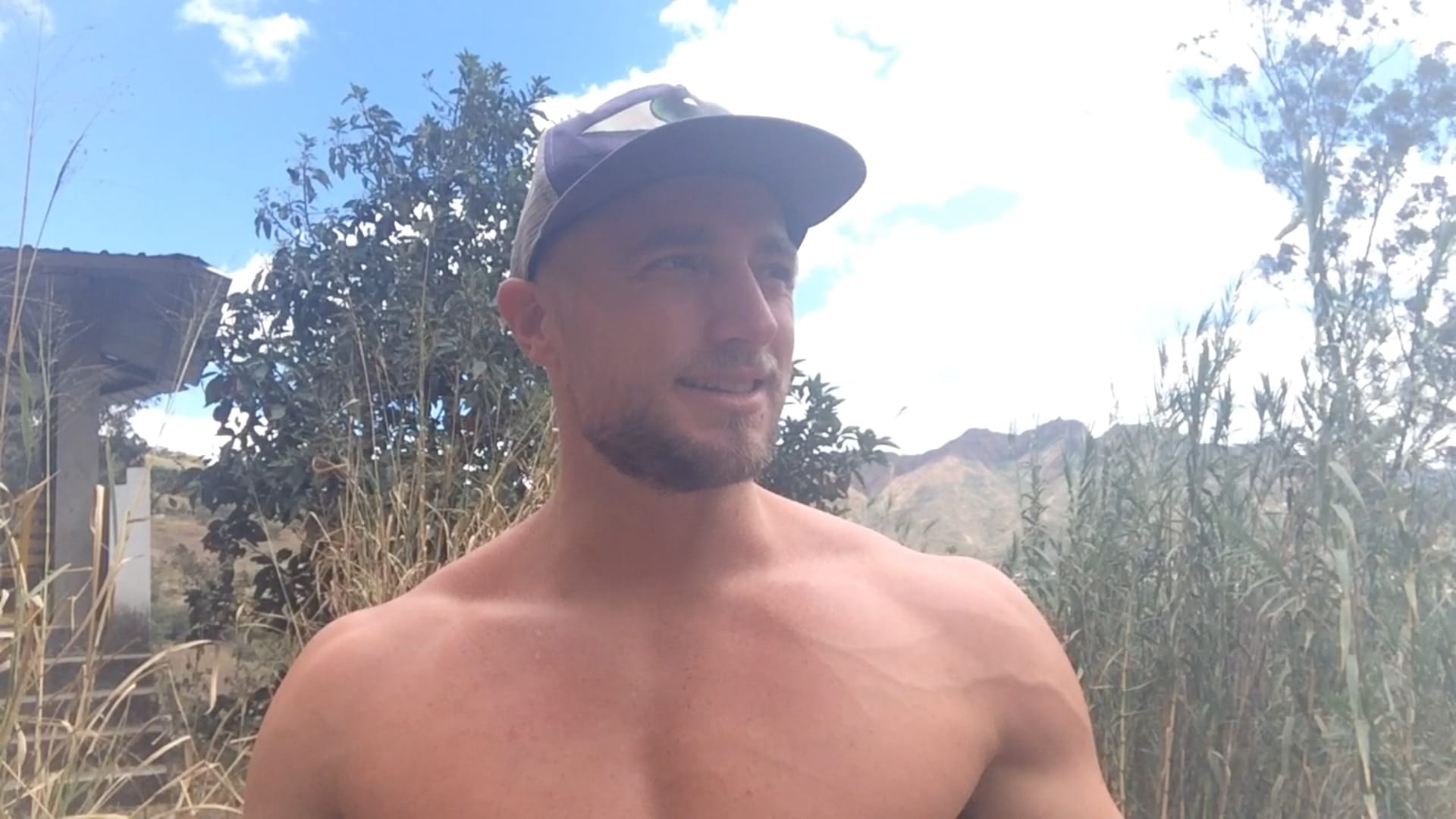 A man wearing a cap outdoor surrounded by tall grass.