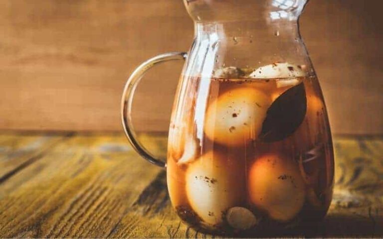 Pickled hard boiled eggs in a jar on a wooden surface.