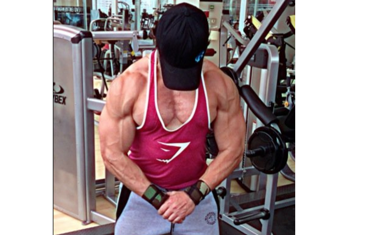 A man in the gym flexing his upper body muscle.