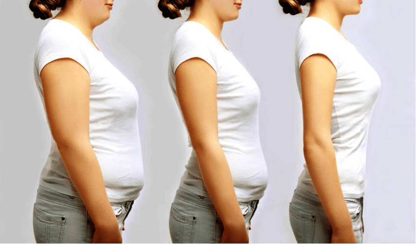 A woman in white top standing to show the progress on her figure.