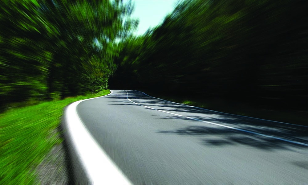 Empty road with blurred trees on the right and left side.