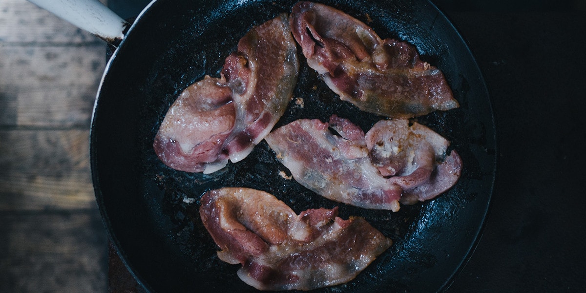 Four pieces of bacon in a pan.