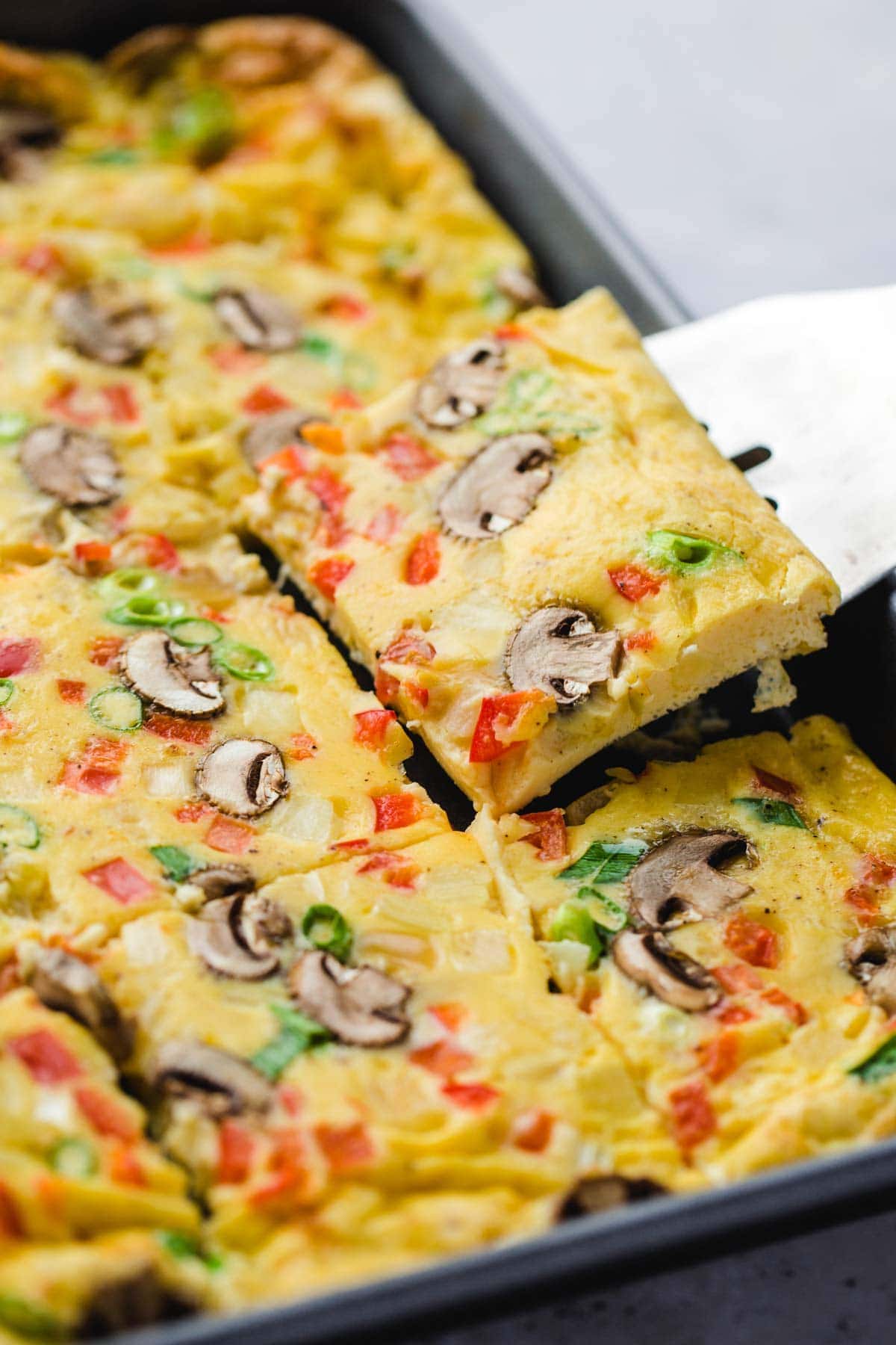 Omelet slices with mushrooms and peppers cooked in a pan.