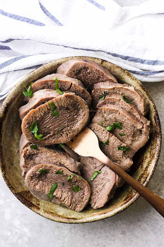 Instant pot beef tongue in a bowl with a fork.