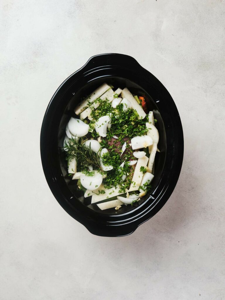 A bowl of fresh keto salad with sliced eggs, herbs, and vegetables on a light grey background.