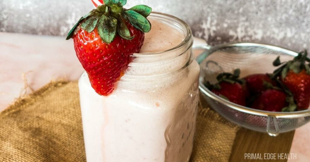 Strawberry smoothie in a glass on a brown surface.