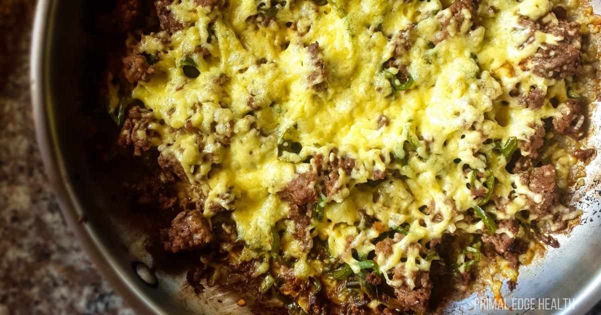 Lower left corner of Philly Cheesesteak casserole in glass baking dish cooling on rack.