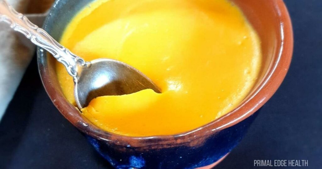 Egg pudding in a blue cup served with a spoon.