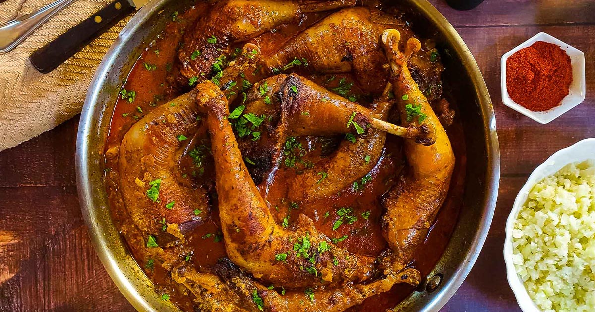 Braised chicken legs in a red paprika sauce.