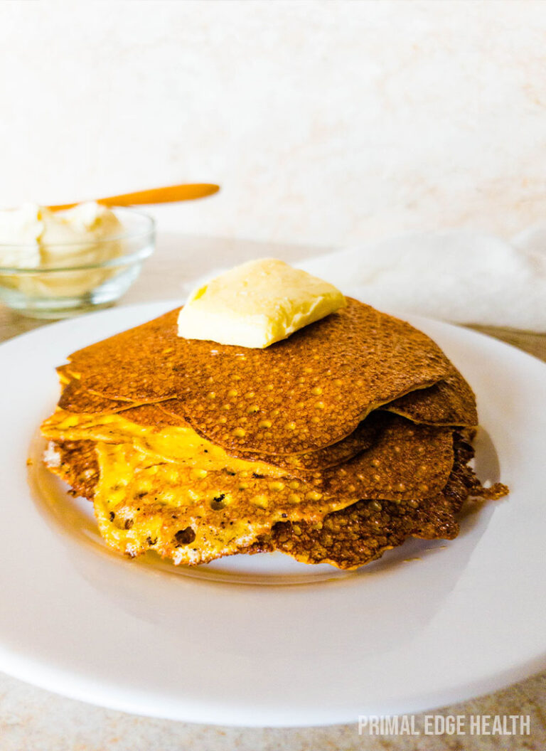 A stack of pancakes with a pat of butter on top on a plate.