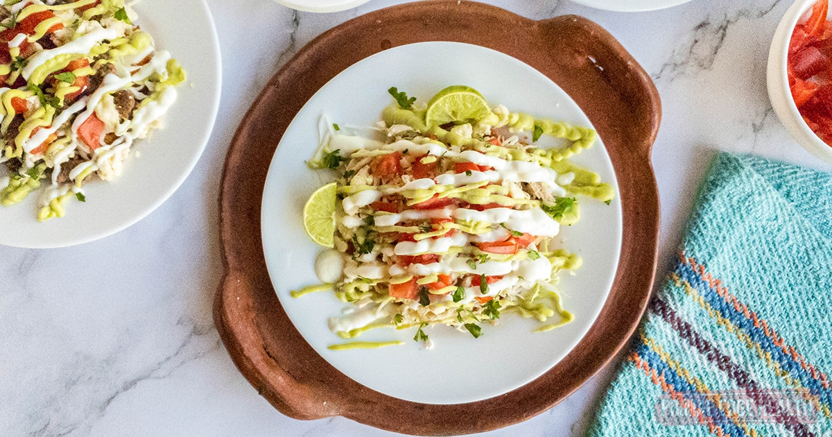 Chicken tostadas with cheese shell on plate on a terra cotta tray.