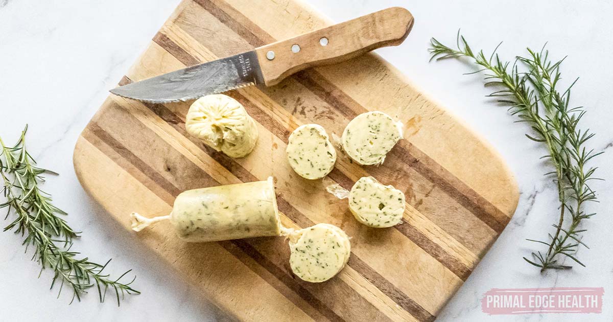 Slices of rosemary garlic butter on a wooden cutting board.