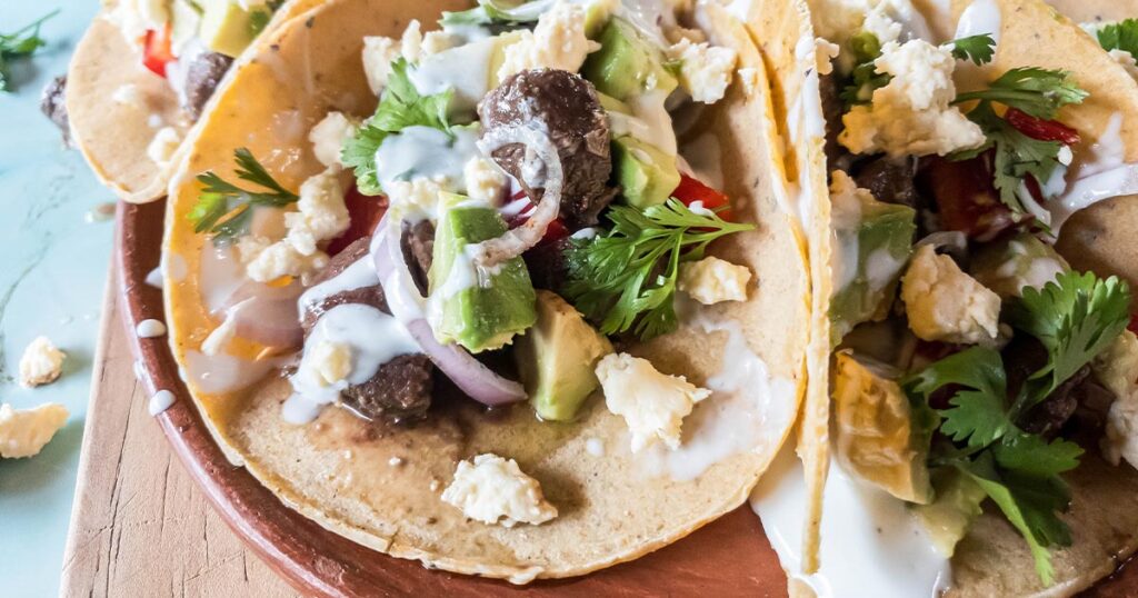 A plate of beef heart tacos on a wooden board.