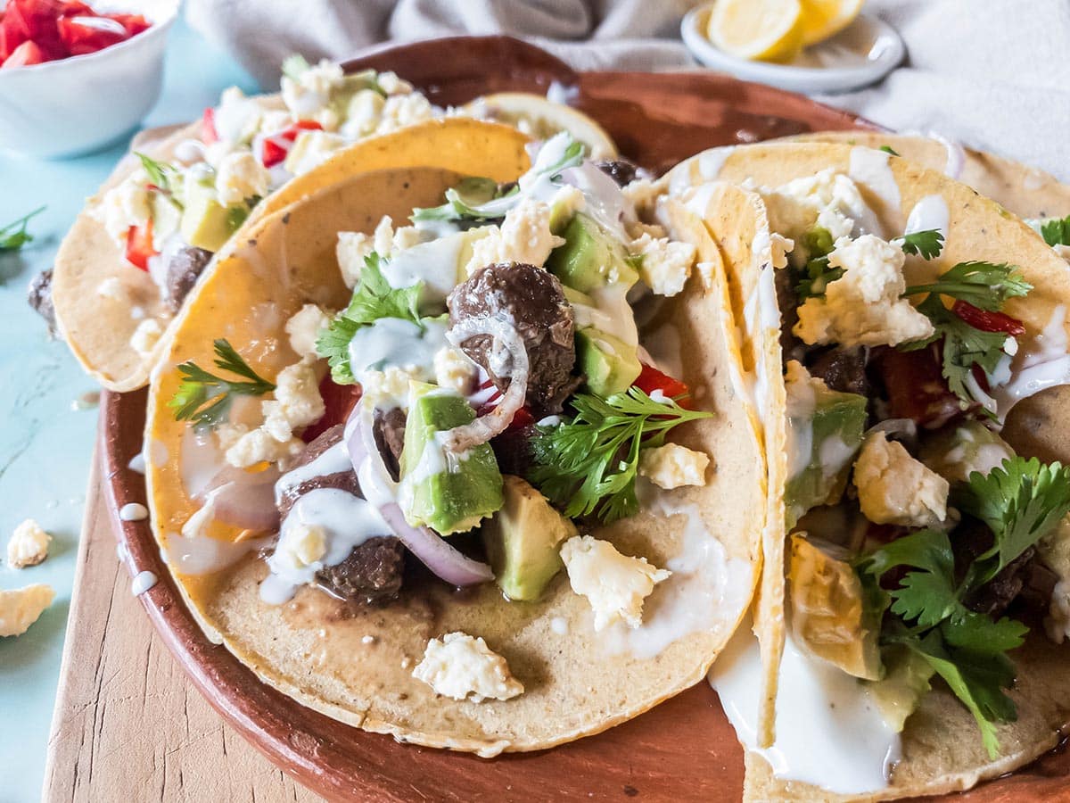 A picture of a close-up on beef heart tacos on a terra cotta tray.