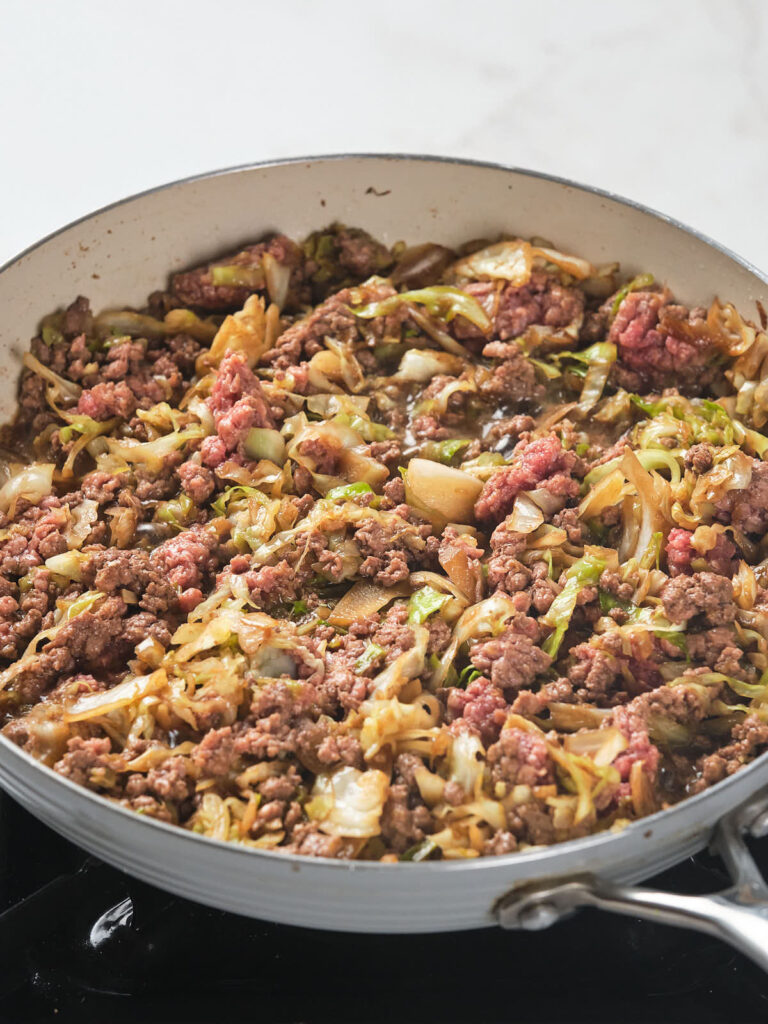A large frying pan filled with a mixture of cooked ground beef and cabbage.
