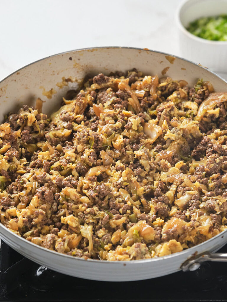 A skillet filled with a cooked mixture of ground meat, cabbage, and other vegetables.