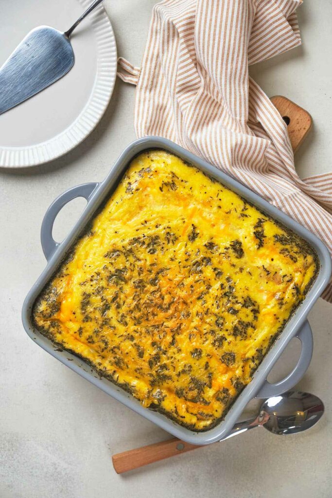 A casserole dish containing a baked dish with a golden crust, seasoned with herbs.