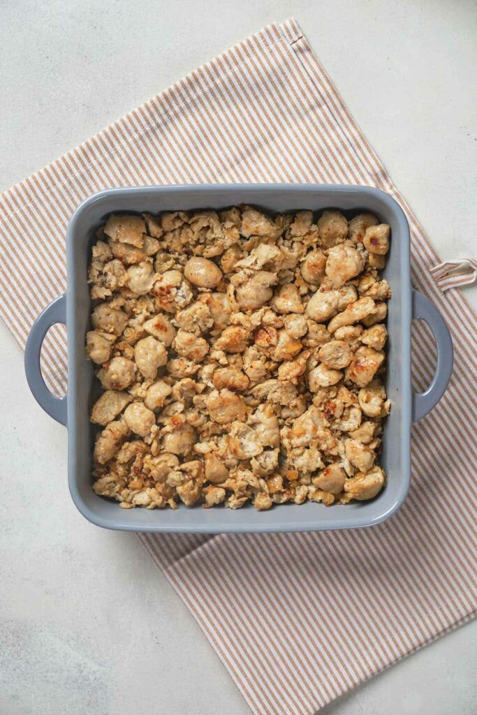 A blue square baking dish filled with crumbled, cooked pieces of textured protein.