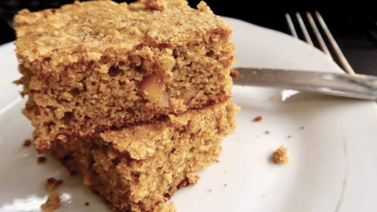 Two pieces of macadamia nut coffee cake on top of each other on a white plate.