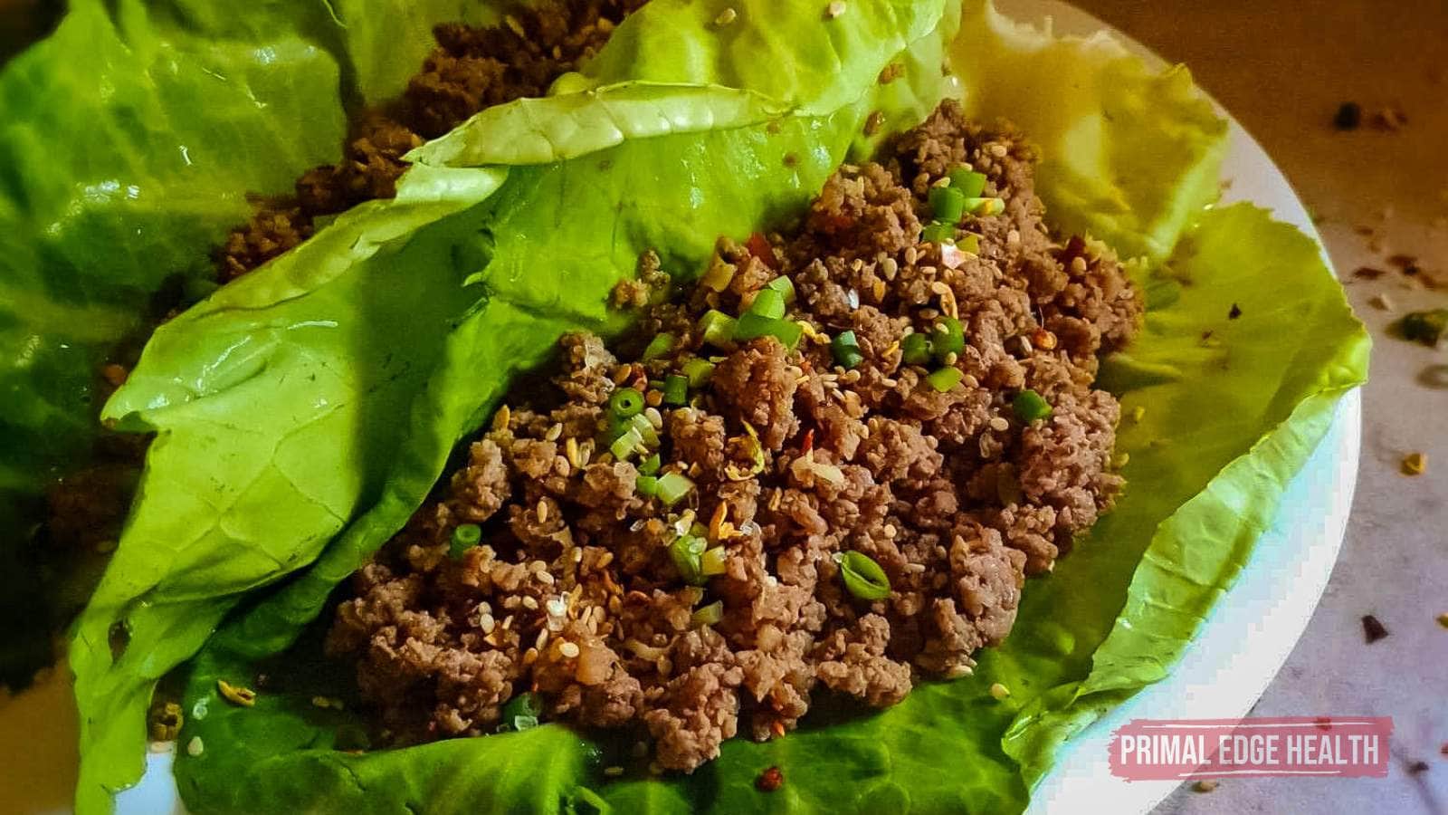 Lettuce wraps filled with seasoned ground beef and garnished with chopped green onions.