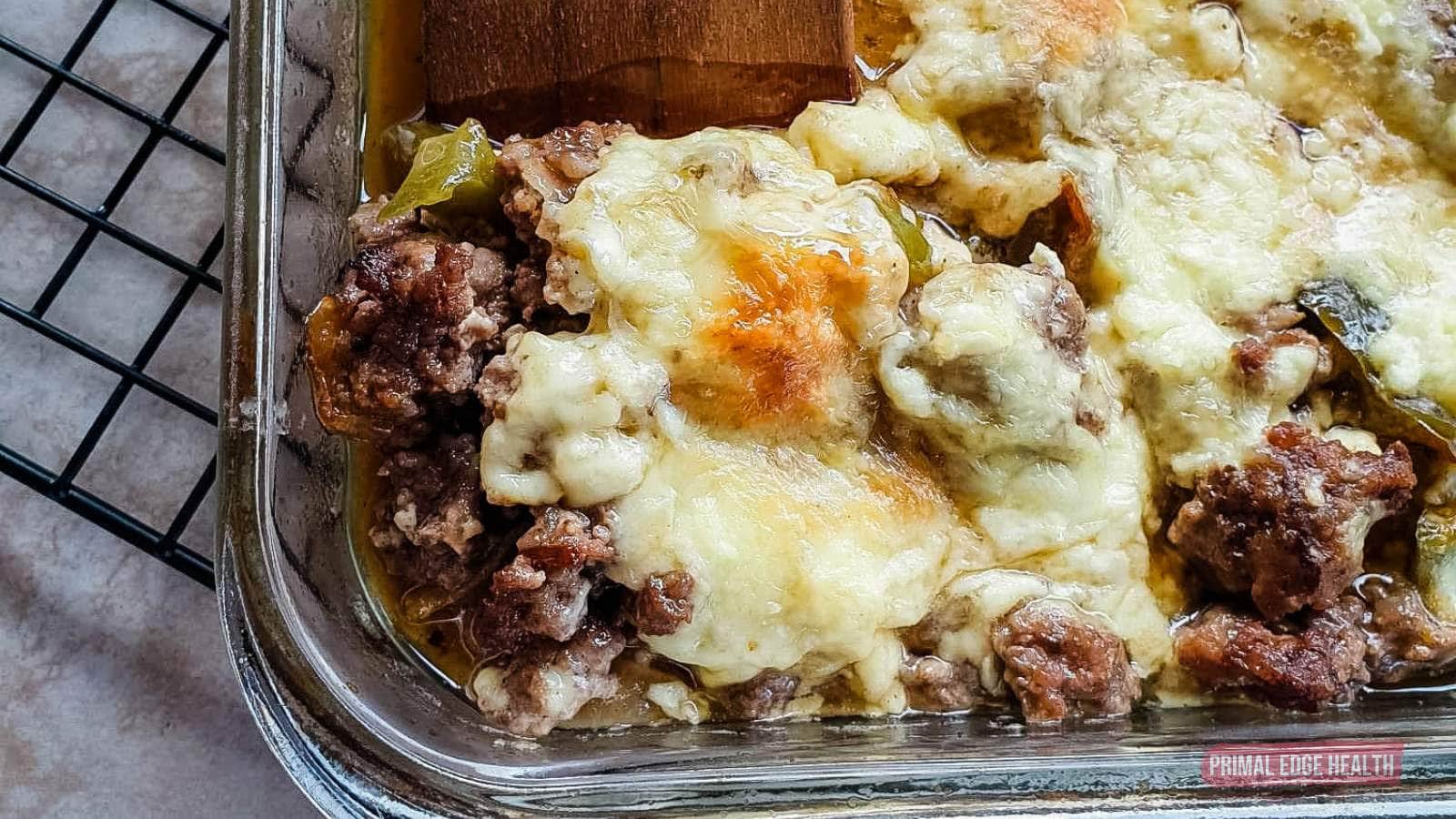 A close-up of a baked casserole dish filled with melted cheese and ground meat, placed on a cooling rack.