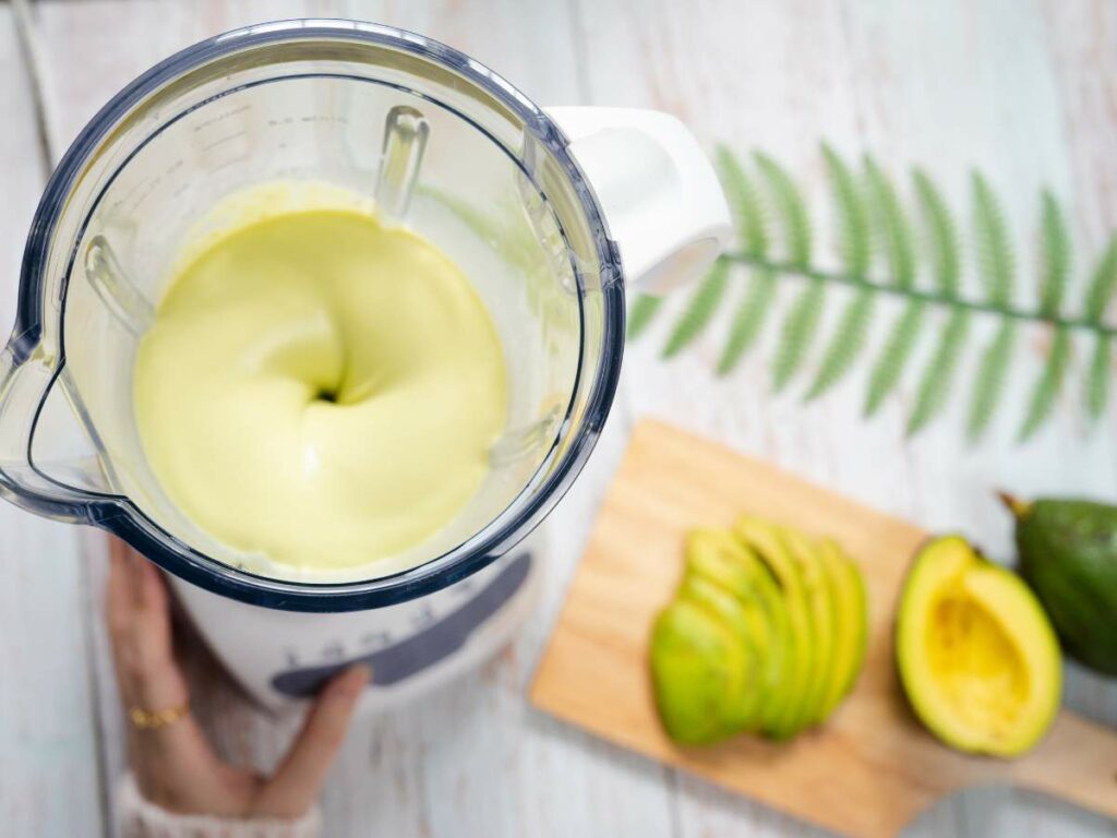 A blender is mixing a creamy avocado blend.