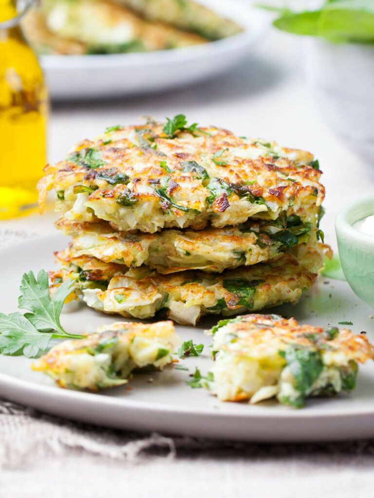 A stack of vegetable fritters garnished with parsley on a gray plate.