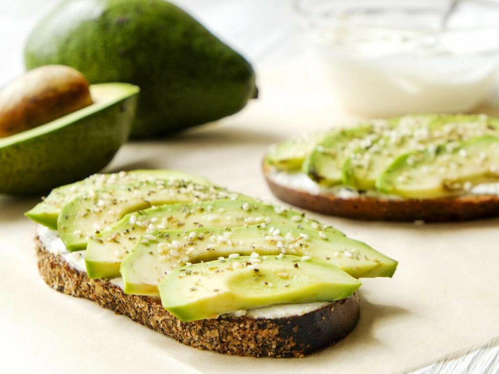 Slices of avocado on whole-grain toast topped with seeds.