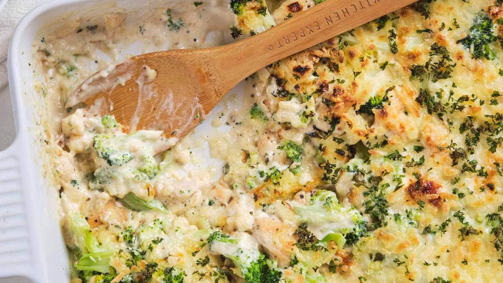 A fork with a piece of chicken broccoli Alfredo casserole on a white plate.