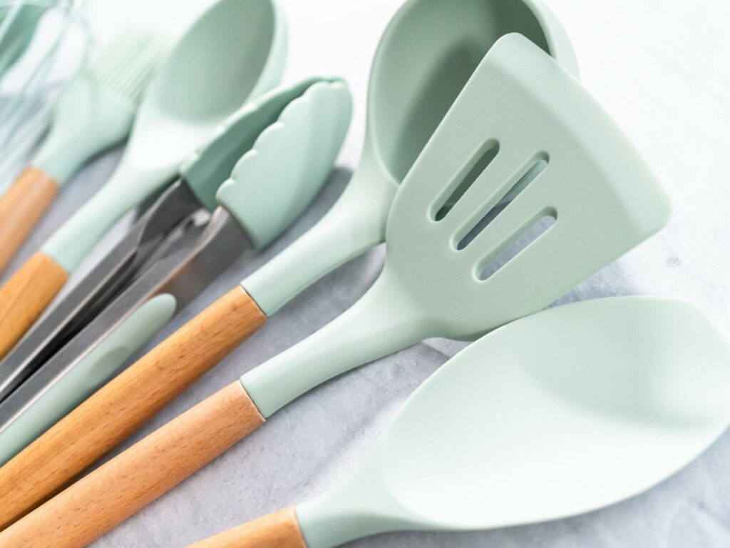 A set of light green kitchen utensils laid out on a white surface.