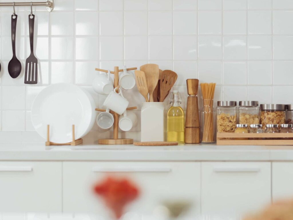 A kitchen counter with utensils arranged neatly against a white tiled backsplash.