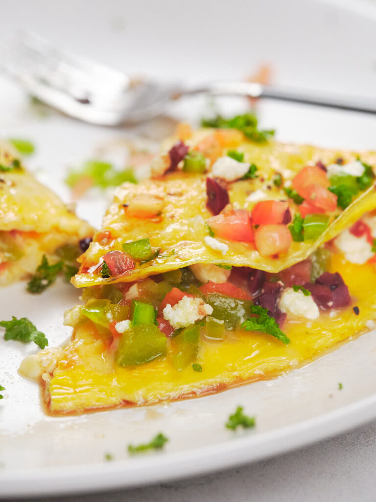 A close-up of a plate of omelet with toppings.