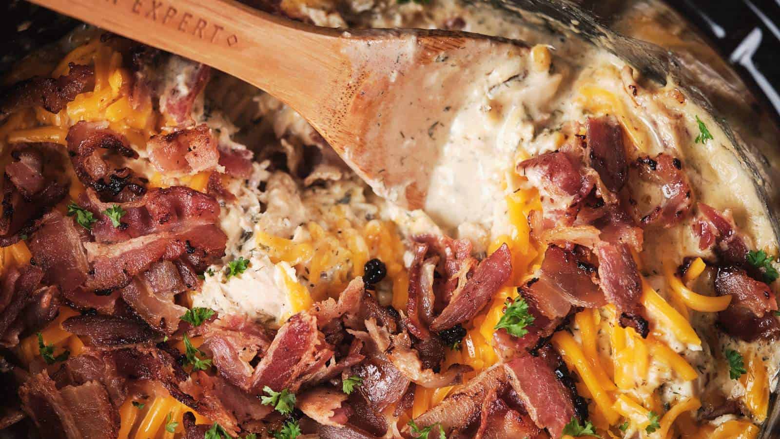 A close-up of slow cooker crack chicken being stirred with a wooden spoon.