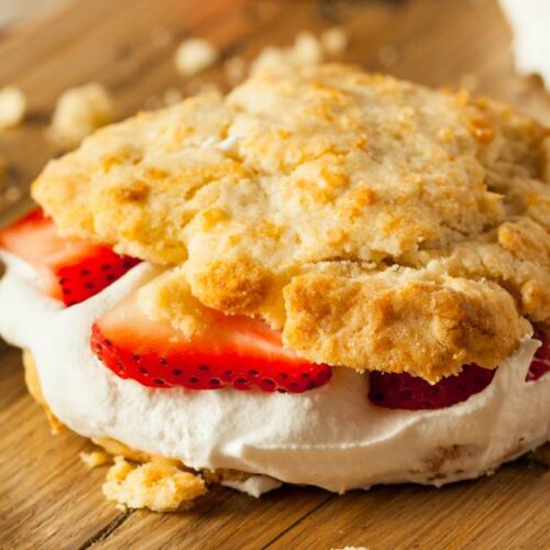 A strawberry shortcake with fresh sliced strawberries and whipped cream between two layers of biscuit.