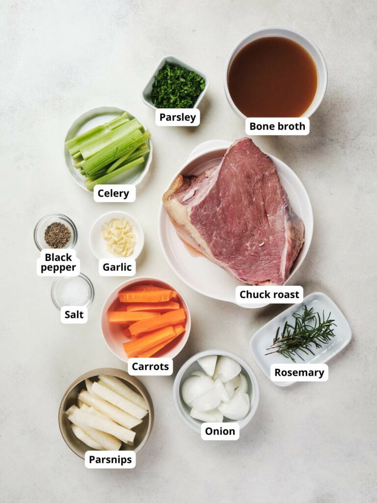 Top-down view of various ingredients for a beef dish arranged in bowls on a white surface.