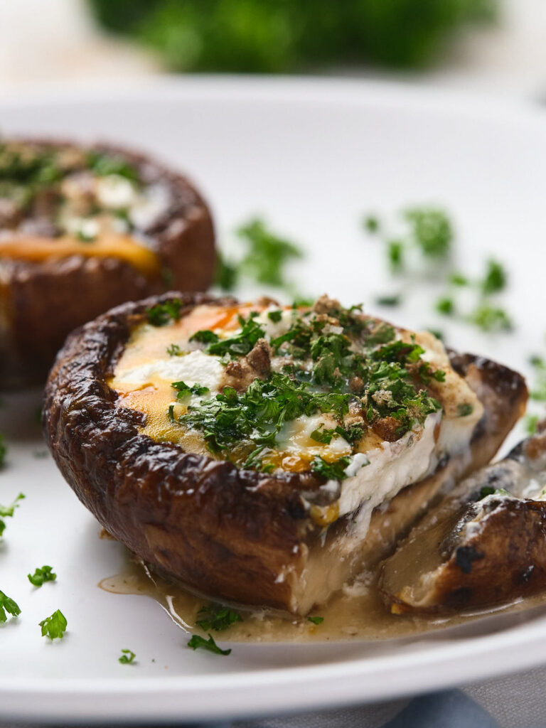 A close-up of egg in mushroom served on a white plate.