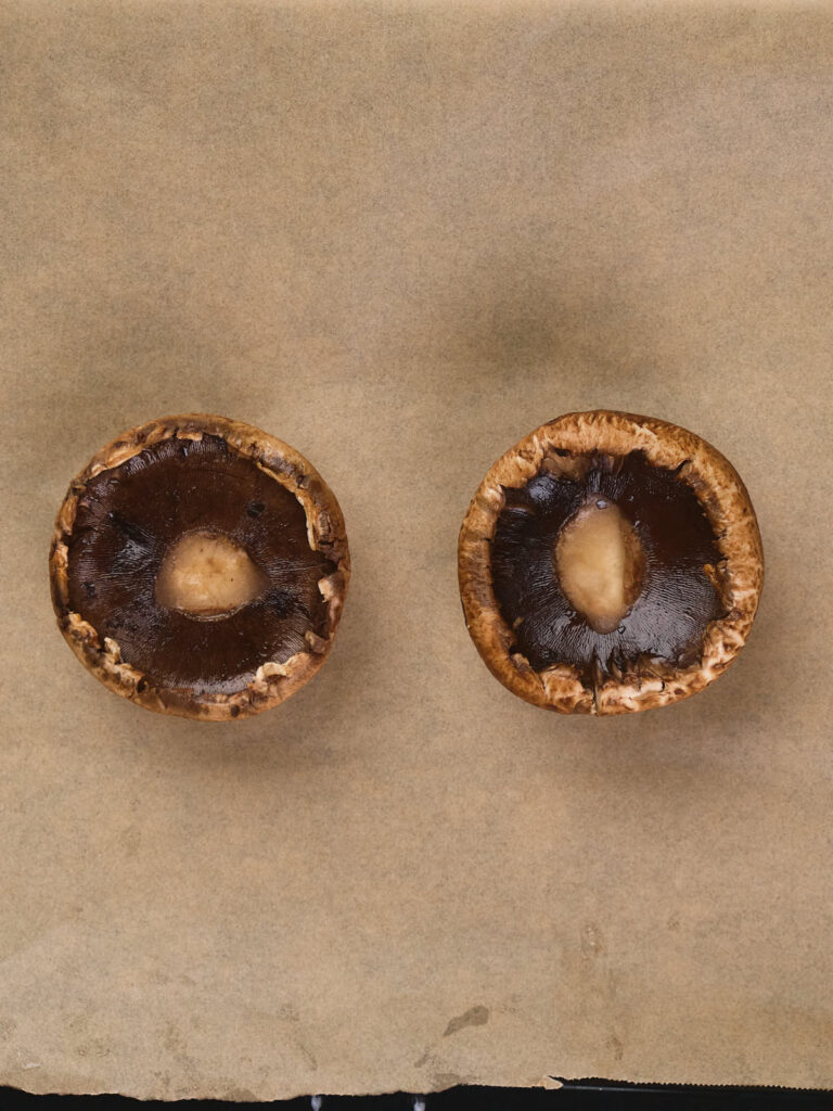 Two mushrooms placed side by side on a sheet of parchment paper.