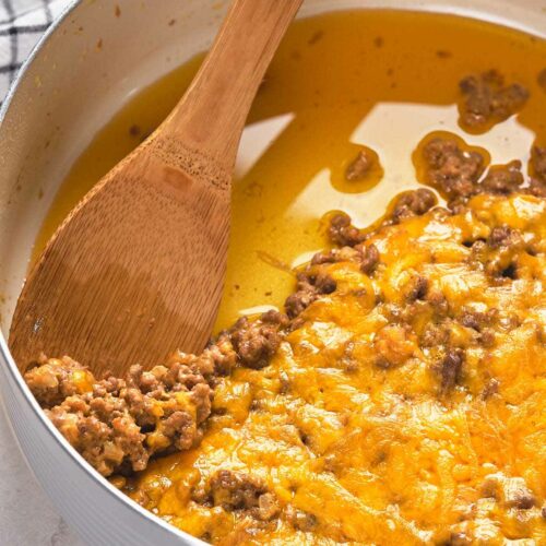 A pan filled with melted cheese and cooked ground meat.