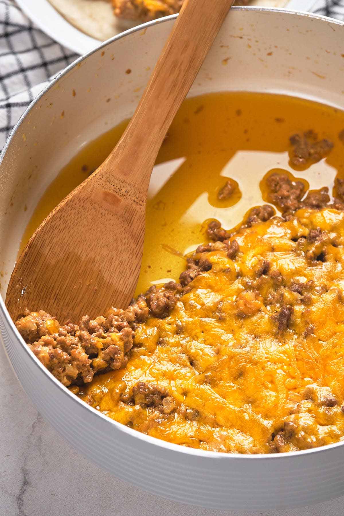 A pan filled with melted cheese and cooked ground meat.