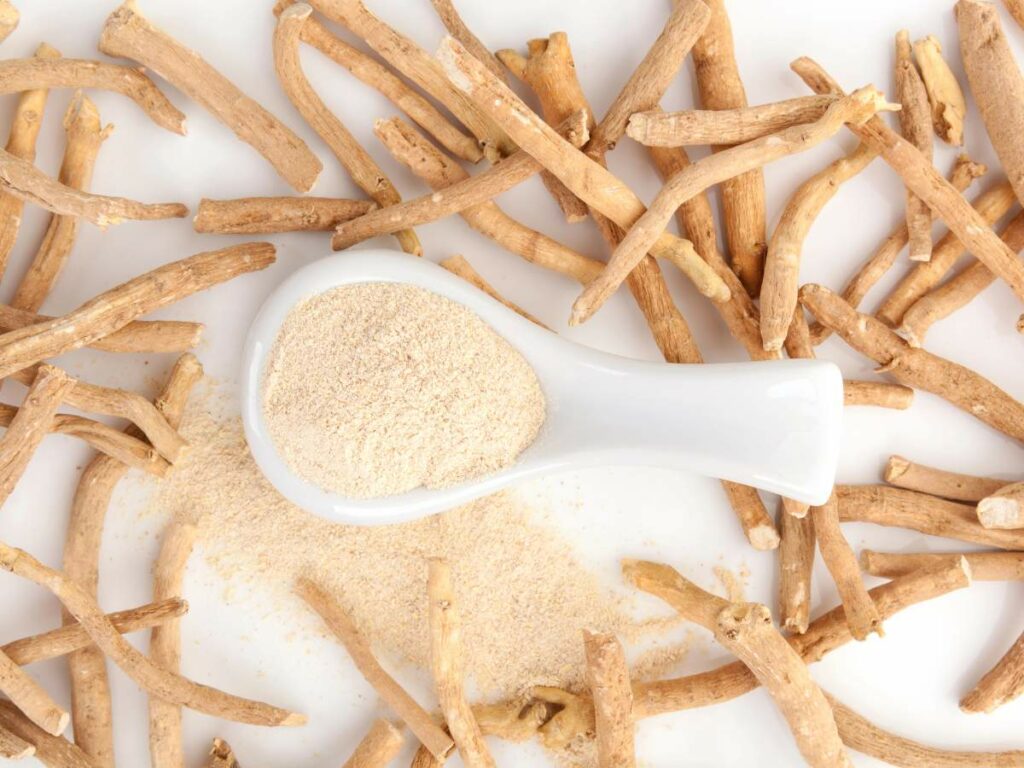 Ginger powder on a white spoon laying on a white surface.