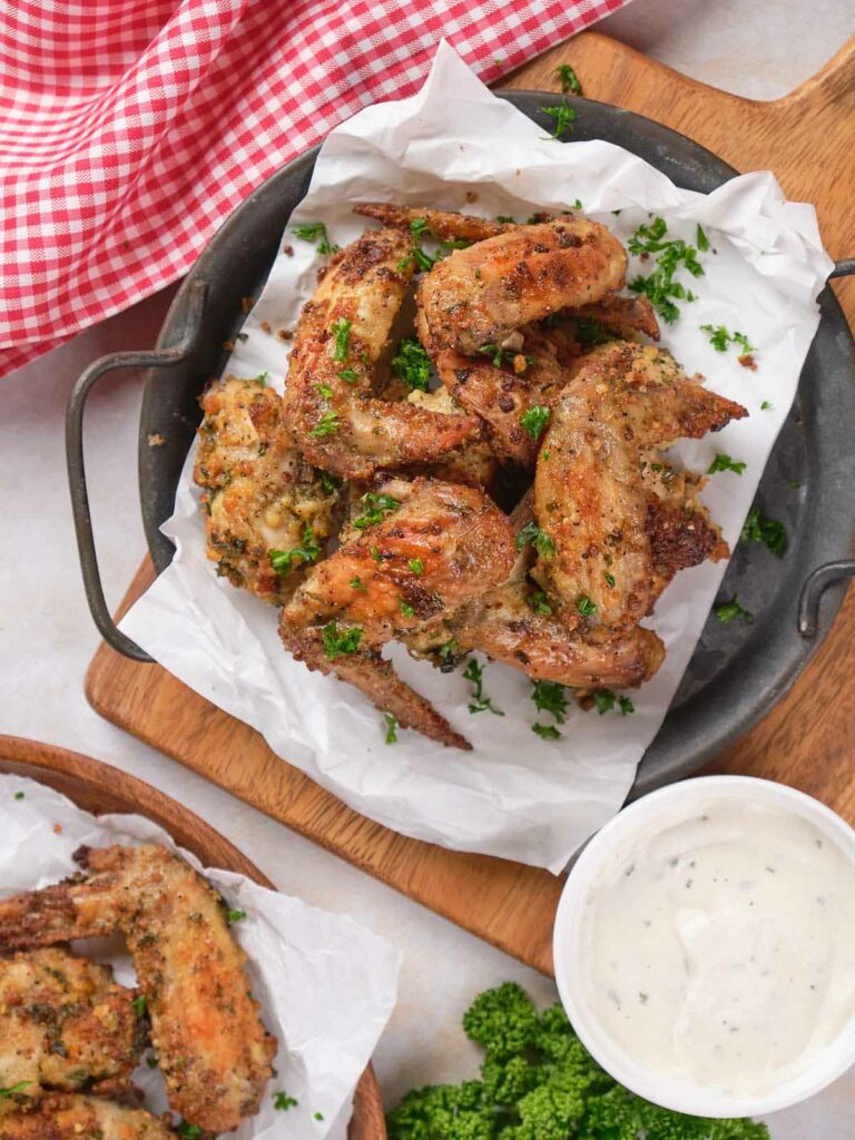 A plate parmesan chicken wings, served on parchment paper.