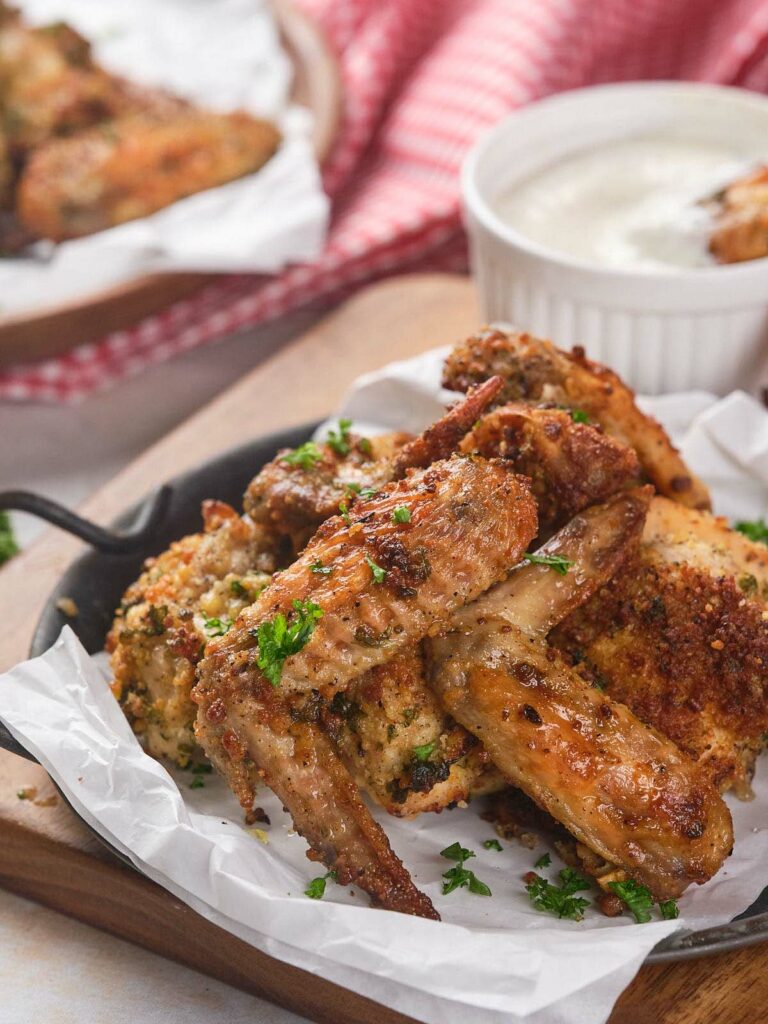 Crispy parmesan chicken wings served on parchment paper.