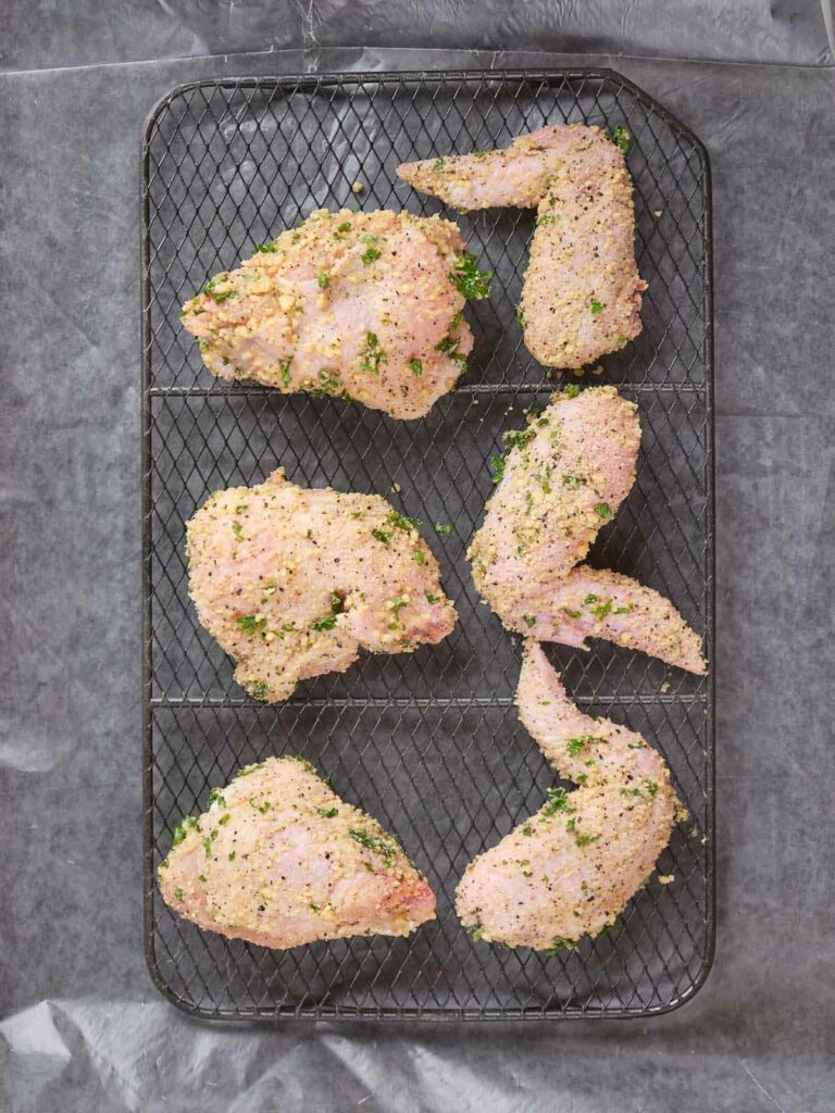 Raw, breaded chicken pieces arranged on a wire rack.