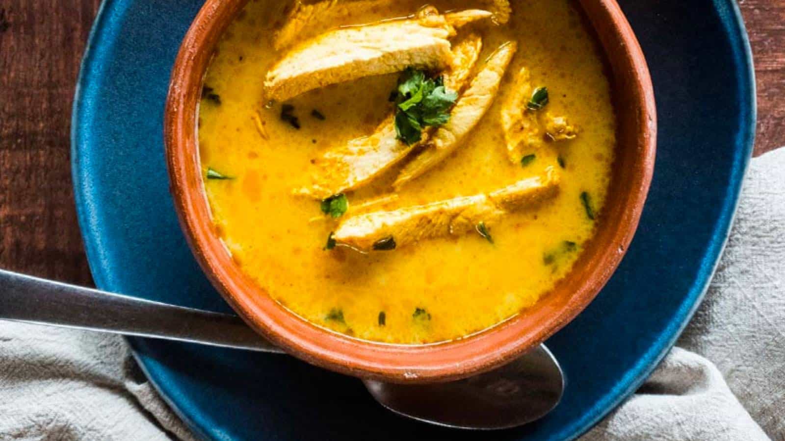 Tom kha gai soup in a brown bowl with a spoon.