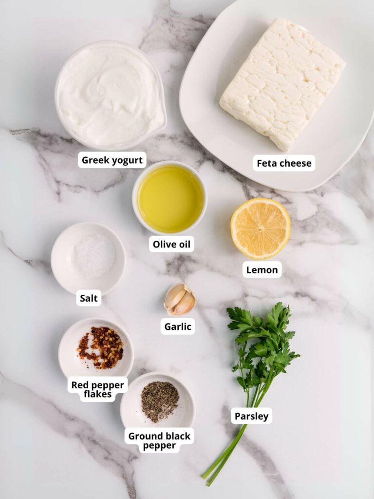 Ingredients for feta dip arranged on a marble surface.