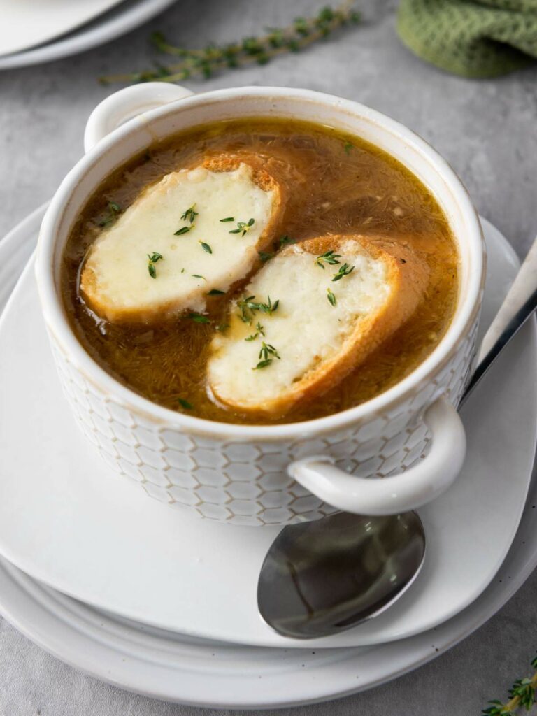 A bowl of French onion soup with two slices of bread topped with melted cheese.