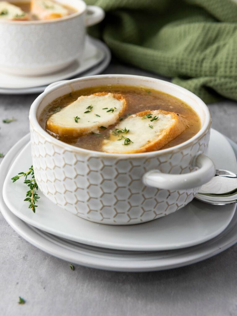 A bowl of soup topped with two slices of toasted bread and melted cheese.