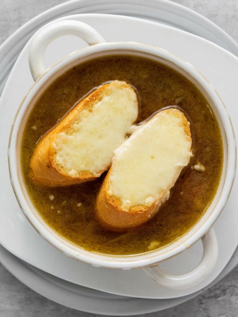 A bowl of French onion soup topped with two slices of bread covered in melted cheese.