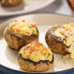 Stuffed mushrooms filled with a creamy mixture, topped with a golden-brown crust.