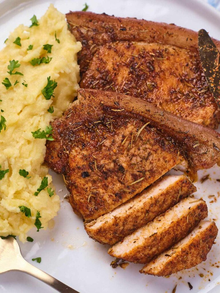 Air fryer boneless pork chops with herbs, served beside creamy mashed potatoes.